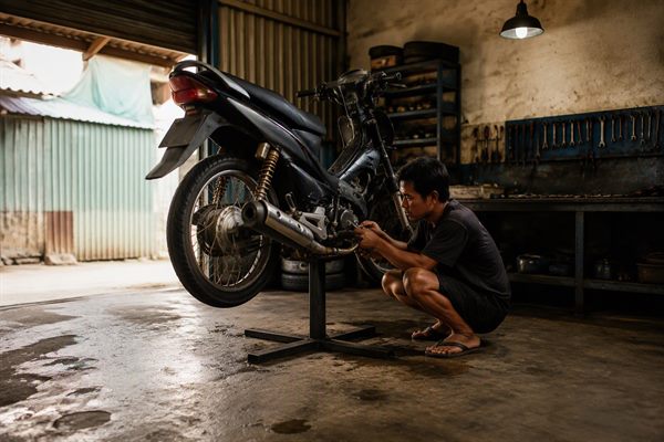 Perkakas bengkel motor tertata di dinding dengan satu sepeda motor sedang diperbaiki