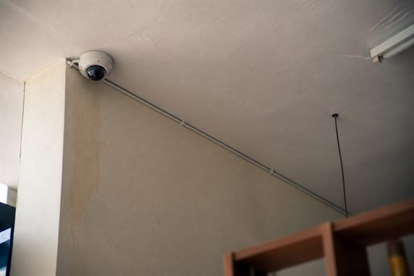 Kamera pengawas kecil terpasang di sudut langit-langit atas meja kasir sebuah toko